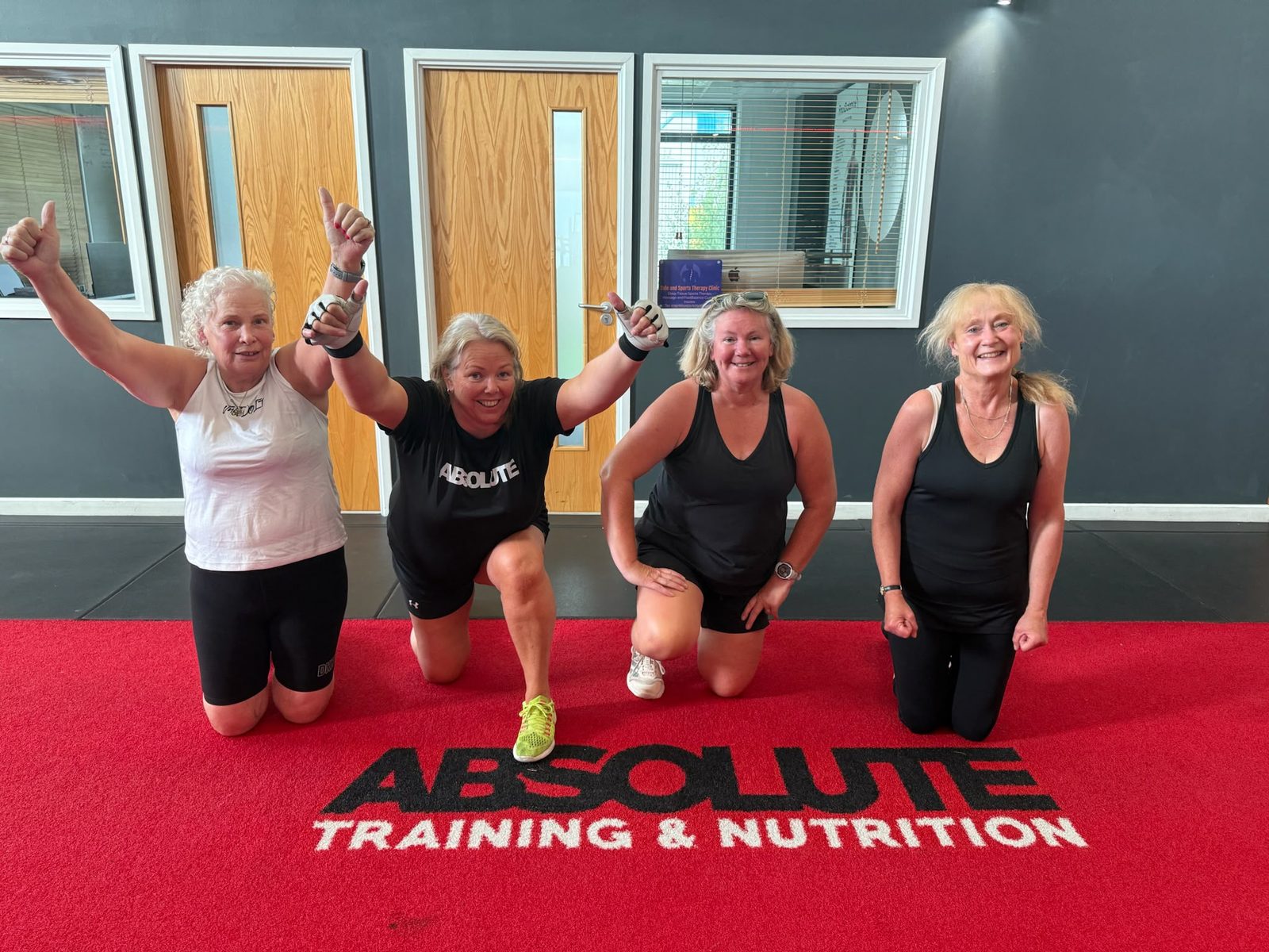 Four Absolute members celebrating on the red Absolute Training & Nutrition carpet